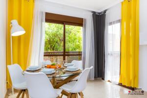 comedor con cortinas amarillas, mesa y sillas en Blanco Apartment, en San Pedro del Pinatar