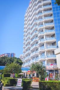 a tall white building with trees in front of it at Hotel Rеgina - Golden Sands All Inclusive in Golden Sands