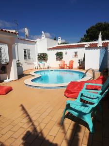 a patio with a swimming pool and a blue chair at Villa Quica, heated pool in Albufeira
