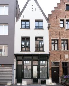 Boutique Holiday Home ZaligInAntwerpen 77 في أنتويرب: مبنى أبيض بأبواب ونوافذ سوداء