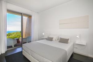 a white bedroom with a bed and a large window at Mosteiros Place in Mosteiros +37 photos