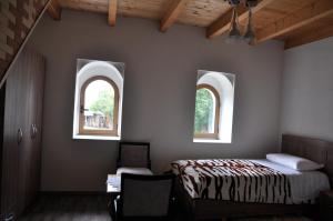 a bedroom with two windows and a bed and a chair at Bujtina Gjana in Kukës