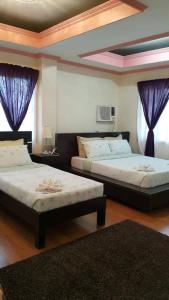 two beds in a room with purple curtains at Florabells Iraya Guest House - Batanes in Basco