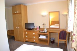 a bedroom with a desk with a television and a mirror at Chichester Park Hotel in Chichester