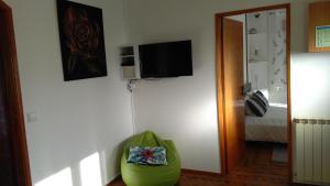 a room with a green chair and a television on a wall at O Nosso Cantinho in Louriçal