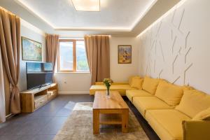 a living room with a yellow couch and a tv at Villa ADELHEIDE - Spa & BBQ in Beli Iskar