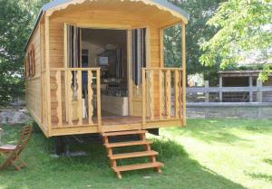 een houten hut met een trap in het gras bij les roulottes de dilou Cerise in Matha