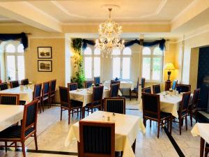 a restaurant with tables and chairs and a chandelier at Hotel am Bayrischen Platz in Leipzig