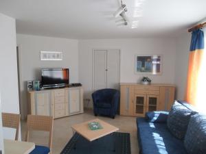 a living room with a blue couch and a tv at Gaestehaus Vogelsang in Sierksdorf +26 photos