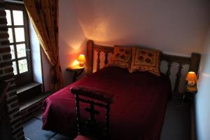 a bedroom with a bed with a red comforter and a window at Le Pommenial de la Hérissonnière in Saint-Aubin-de-Bonneval