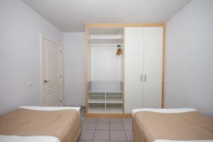 a room with two beds and a closet with shelves at Servatur Terrazamar Sun Suite in Puerto Rico de Gran Canaria