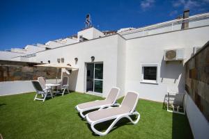a patio with white chairs and a table on grass at Servatur Terrazamar Sun Suite in Puerto Rico de Gran Canaria