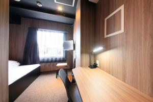 een kamer met een bureau, een bed en een raam bij Tabist CapsuleHotel APODS Himeji Station in Himeji