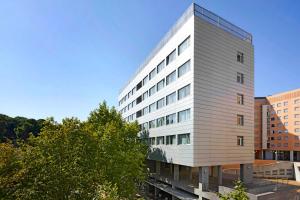 a tall white building with trees in front of it at Exe Plaza Delicias in Zaragoza