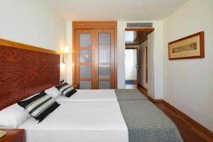 a bedroom with a large white bed with a wooden headboard at Exe Plaza Delicias in Zaragoza