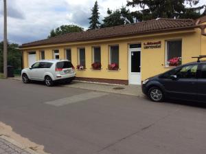 two cars parked in front of a yellow building at Ubytování Lábadi in Rohatec
