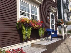 a blue chair sitting on the porch of a house with flowers at The Narrows B&B in St. John's