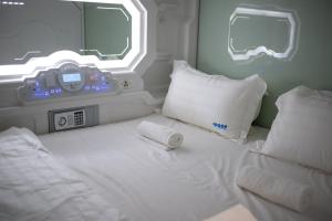 a bedroom with a white bed with a clock on it at Space Hotel @ Chinatown Kuala Lumpur in Kuala Lumpur