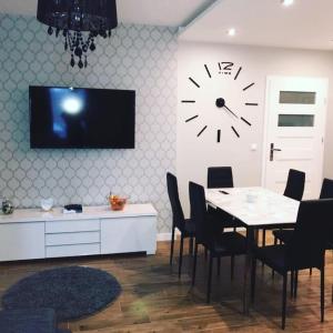 a dining room with a table and a clock on the wall at Domek Przy Źródełku in Muszyna