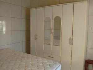 1 dormitorio con armarios blancos y 1 cama en Residencia Siqueira, en Garopaba