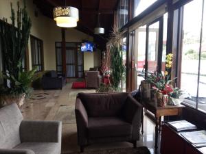 a lobby with chairs and windows in a building at Hotel Bemtevi in Farroupilha