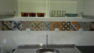 a kitchen with a sink and a shelf with cups at Casa Barra de Ibiraquera. Há menos de 5minutos caminhando da lagoa e do mar. in Barra de Ibiraquera