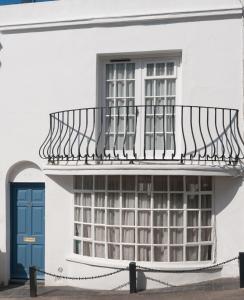 a balcony on the side of a white building with a blue door at Sea Breeze Cottage with Parking in Brighton & Hove