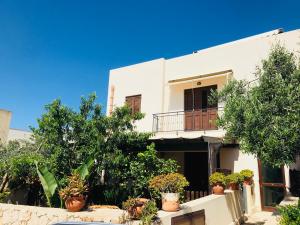a white house with potted plants in front of it at Appartamento BluOltreMare in San Vito lo Capo