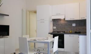 - une cuisine avec des placards blancs, une table et des chaises dans l'établissement Bologna Welcome House, à Bologne
