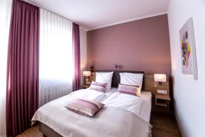 a bedroom with a bed with white sheets and pink pillows at Hotel Restaurant Verst in Gronau
