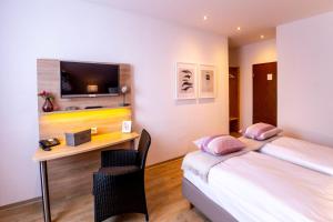 Schlafzimmer mit einem Bett und einem Schreibtisch mit einem TV in der Unterkunft Hotel Restaurant Verst in Gronau