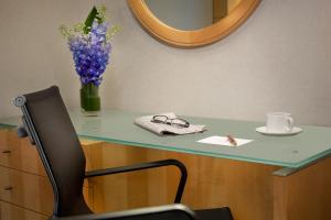 a desk with a vase of purple flowers and a chair at Millennium Premier New York Times Square in New York