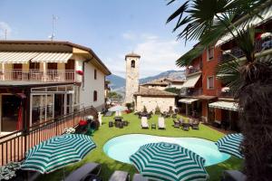 an outdoor patio with umbrellas in a town with a clock tower at Albergo Casa Este in Brenzone sul Garda