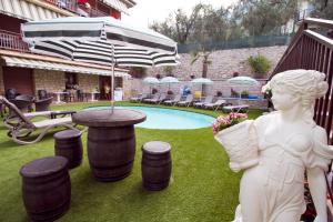 a statue of a woman standing next to a pool with an umbrella at Albergo Casa Este in Brenzone sul Garda