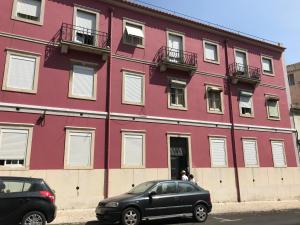 リスボンにあるSweet Apartment with Terrace in Centralの赤い建物の前に停車した車2台