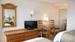 a hotel room with a bed and a television on a dresser at San Simeon Lodge in San Simeon