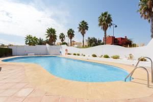 サンルーカル・デ・バラメダにあるBonito apartamento en campo de golf con piscinaのヤシの木が茂るリゾート内のスイミングプール