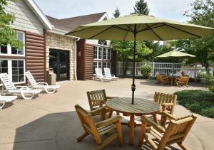 a table and chairs with an umbrella on a patio at Stoney Creek Hotel Wausau - Rothschild in Rothschild