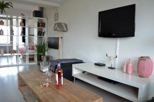 ein Wohnzimmer mit einem Tisch und einem TV in der Unterkunft Beach House SEA-side in Egmond aan Zee