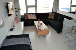ein Wohnzimmer mit einem schwarzen Sofa und einem Couchtisch in der Unterkunft Beach House SEA-side in Egmond aan Zee