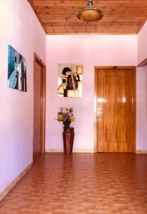 korytarz z drewnianymi drzwiami i wazonem kwiatów w obiekcie Gold Guest House & Bar w mieście Përmet