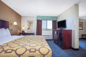 a hotel room with a bed and a television at Baymont by Wyndham Saraland in Saraland
