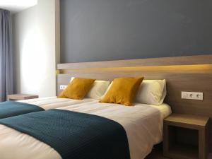 a bedroom with a large bed with yellow pillows at Hotel Alda Estación Pontevedra in Pontevedra
