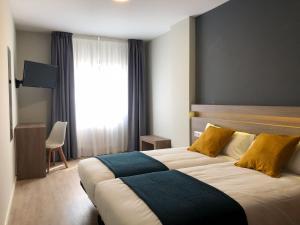 a bedroom with a large bed with yellow and blue pillows at Hotel Alda Estación Pontevedra in Pontevedra