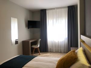 a bedroom with a bed and a window with a chair at Hotel Alda Estación Pontevedra in Pontevedra