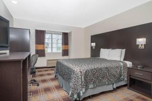 a hotel room with a bed and a flat screen tv at Days Inn by Wyndham Faribault in Faribault
