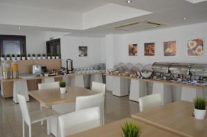 een restaurant met witte stoelen en tafels en een bar bij Les Palmiers Petrou Apartments in Larnaka