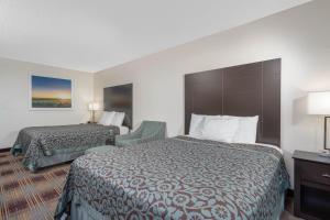 a hotel room with two beds and a chair at Days Inn by Wyndham Faribault in Faribault