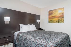a hotel room with a bed and a painting on the wall at Days Inn by Wyndham Faribault in Faribault
