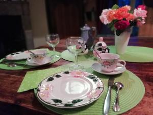 a table with plates and cups and a vase of flowers at le Logis d'Argenson in Beaulieu-sous-Parthenay
